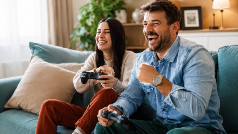 Dvoje igrača uživa u multiplayer gejmingu na kauču